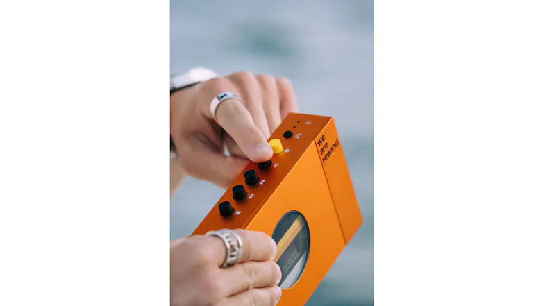 Close-up of hands adjusting the top control buttons on the orange Bluetooth cassette player Close-up of hands adjusting the top control buttons on the orange Bluetooth cassette player
