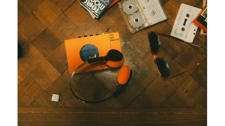 Overhead lifestyle view of the orange Bluetooth cassette player alongside matching headphones Overhead lifestyle view of the orange Bluetooth cassette player alongside matching headphones
