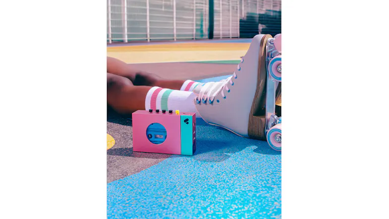 Edith cassette player resting beside roller skates on a colourful outdoor surface Edith cassette player resting beside roller skates on a colourful outdoor surface