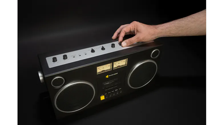 Hand adjusting the top controls of the Bluetooth boombox cassette player, demonstrating the device’s functionality Hand adjusting the top controls of the Bluetooth boombox cassette player, demonstrating the device’s functionality