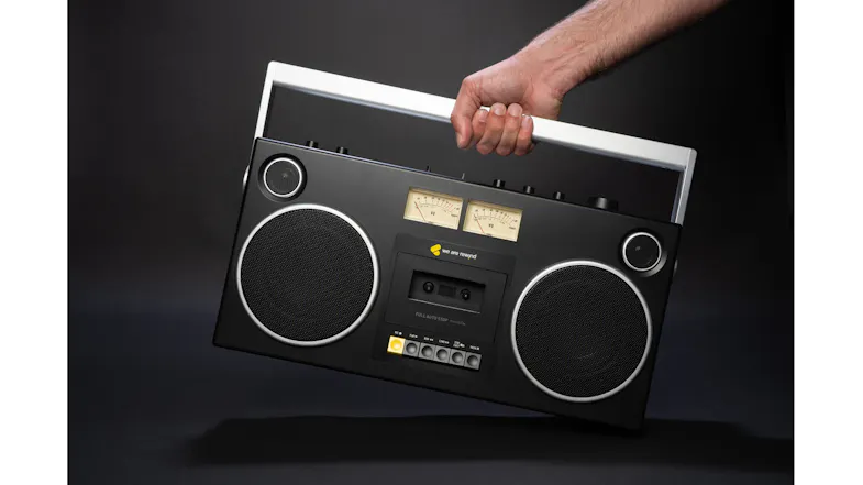 Hand carrying the We Are Rewind Blaster Curtis boombox by its handle, showcasing portability and retro styling Hand carrying the We Are Rewind Blaster Curtis boombox by its handle, showcasing portability and retro styling