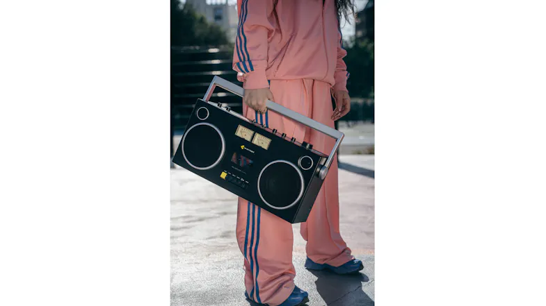 Close-up outdoor shot of the Blaster Curtis boombox held by its handle, emphasising the dual speaker layout Close-up outdoor shot of the Blaster Curtis boombox held by its handle, emphasising the dual speaker layout