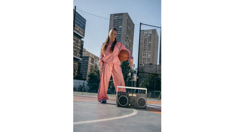 Portable boombox positioned on a basketball court beside a person, illustrating on-the-go music playback Portable boombox positioned on a basketball court beside a person, illustrating on-the-go music playback