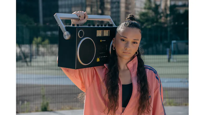 Person carrying the We Are Rewind Blaster Curtis boombox on their shoulder, highlighting its portable design Person carrying the We Are Rewind Blaster Curtis boombox on their shoulder, highlighting its portable design