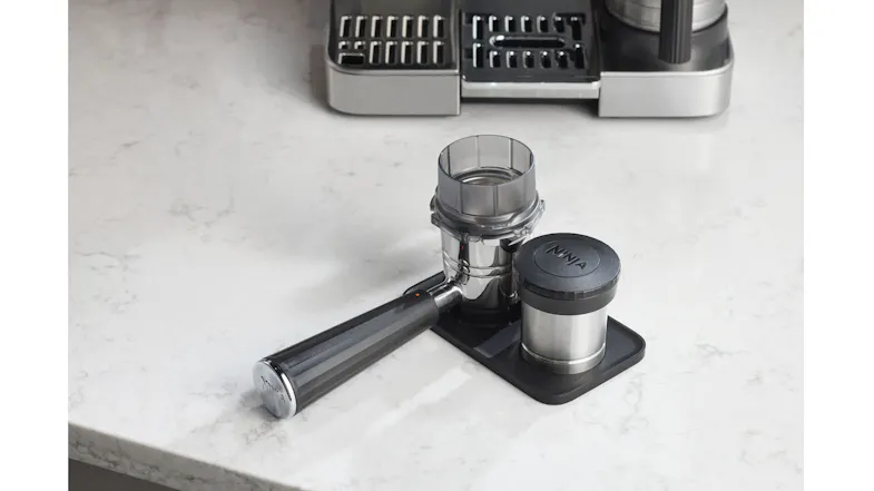 Ninja portafilter with dosing funnel and tamper neatly stored on a black tamping mat Ninja portafilter with dosing funnel and tamper neatly stored on a black tamping mat