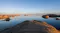 A wide view of calm, reflective water interspersed with desert rock islands during twilight A wide view of calm, reflective water interspersed with desert rock islands during twilight