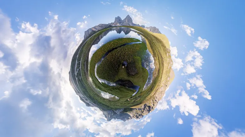 360-degree tiny planet effect of a person sitting in a grassy meadow near mountains and a winding stream 360-degree tiny planet effect of a person sitting in a grassy meadow near mountains and a winding stream