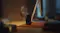 Compact black action camera standing upright on a desk mat next to a desktop monitor in warm indoor light Compact black action camera standing upright on a desk mat next to a desktop monitor in warm indoor light