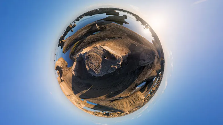 Tiny planet 360 projection of a person standing atop a desert rock formation surrounded by calm water Tiny planet 360 projection of a person standing atop a desert rock formation surrounded by calm water
