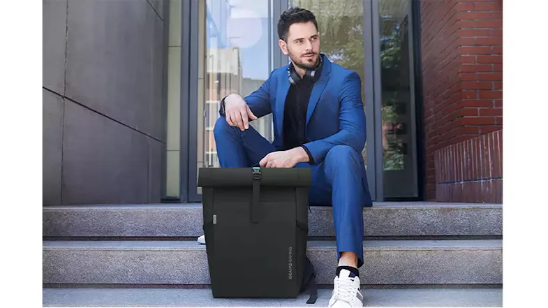 Man in blue suit sitting on steps with black Lenovo gaming backpack beside him on stone steps Man in blue suit sitting on steps with black Lenovo gaming backpack beside him on stone steps