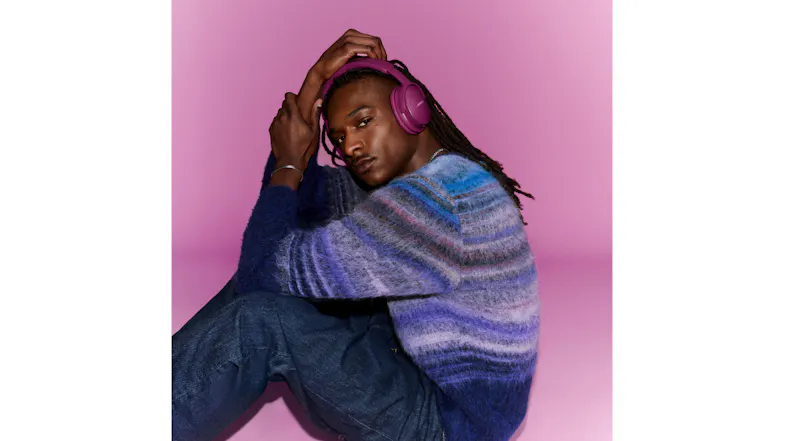 Person sitting down featuring magenta headphones over his ears Person sitting down featuring magenta headphones over his ears