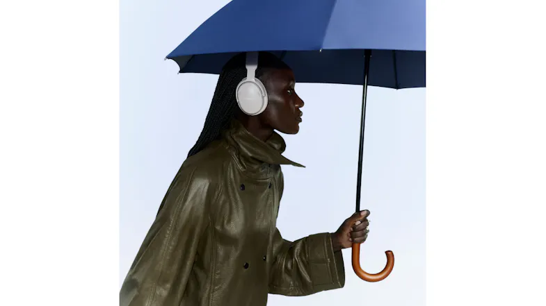 Woman under umbrella showcasing wireless headphones in rain Woman under umbrella showcasing wireless headphones in rain