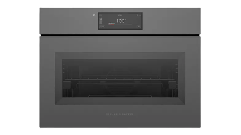 Front view of a grey Fisher & Paykel compact oven with a small digital screen displaying 100 degrees Front view of a grey Fisher & Paykel compact oven with a small digital screen displaying 100 degrees