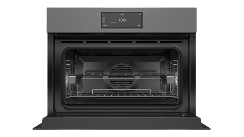 Front view of an open Fisher & Paykel compact oven showing internal wire racks, a fan, and a lit digital screen Front view of an open Fisher & Paykel compact oven showing internal wire racks, a fan, and a lit digital screen
