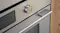 Close-up of a brushed silver glass oven control panel featuring a metallic dial knob, digital display, and sleek handle Close-up of a brushed silver glass oven control panel featuring a metallic dial knob, digital display, and sleek handle