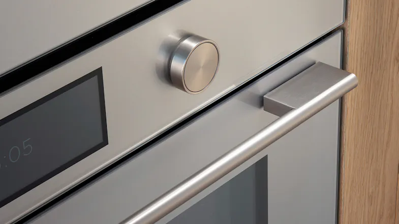 Close-up of a brushed silver glass oven control panel featuring a metallic dial knob, digital display, and sleek handle Close-up of a brushed silver glass oven control panel featuring a metallic dial knob, digital display, and sleek handle