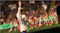 Female soccer player raising her arm, showcasing a cheering crowd Female soccer player raising her arm, showcasing a cheering crowd
