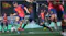 Match scene highlighting players in red and blue kits on the pitch Match scene highlighting players in red and blue kits on the pitch