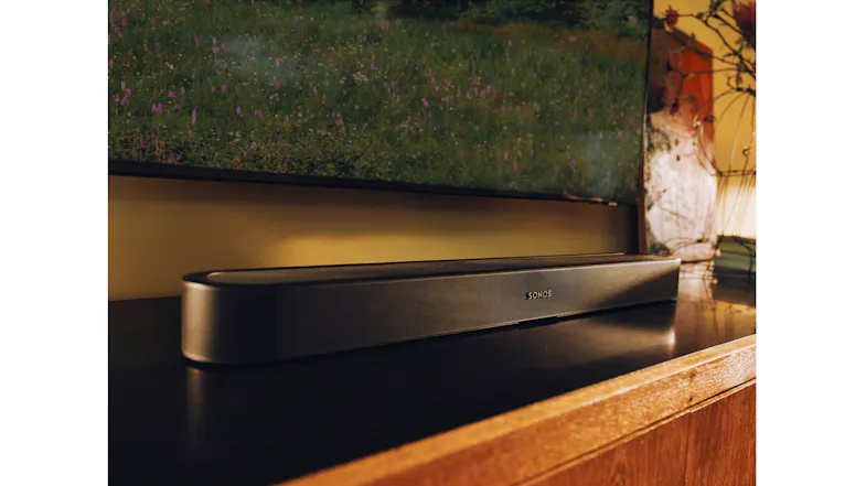 Lifestyle close-up of the Sonos Beam Ultra soundbar positioned beneath a television Lifestyle close-up of the Sonos Beam Ultra soundbar positioned beneath a television