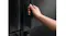 Hand opening a black refrigerator door featuring a recessed handle Hand opening a black refrigerator door featuring a recessed handle
