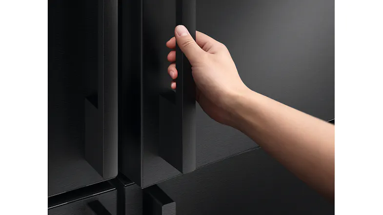 Hand opening a black refrigerator door featuring a recessed handle Hand opening a black refrigerator door featuring a recessed handle