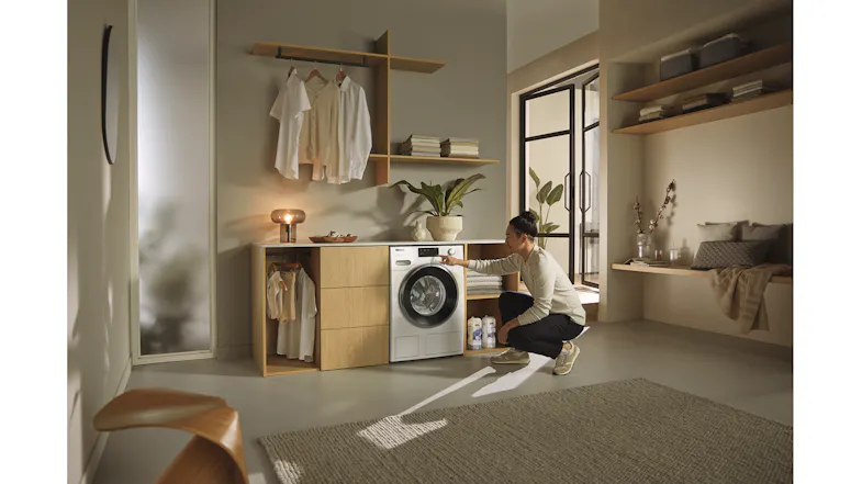 A man operating the Miele washing machine in a modern laundry room A man operating the Miele washing machine in a modern laundry room