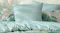 Teal pinstripe pillow sham and matching bedding layered with tropical palm print cushions Teal pinstripe pillow sham and matching bedding layered with tropical palm print cushions