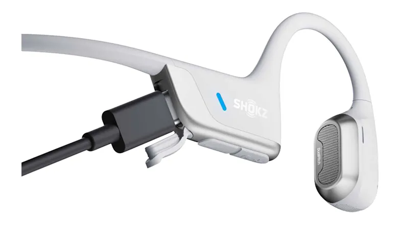 Close-up view of the Shokz headphones featuring a plugged-in charging cable Close-up view of the Shokz headphones featuring a plugged-in charging cable