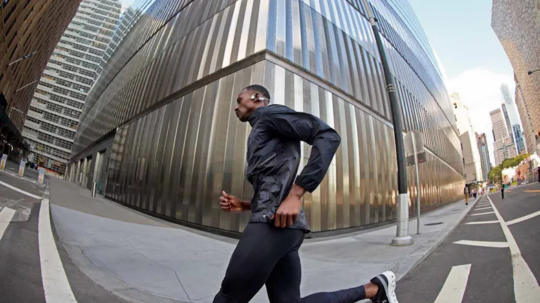 Side view of a man running on a street, highlighting silver headphones Side view of a man running on a street, highlighting silver headphones