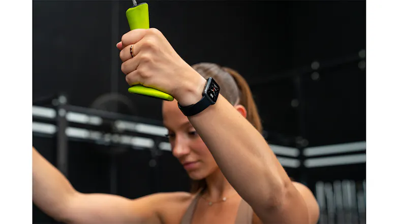 A person using gym equipment while wearing a smartwatch, demonstrating fitness tracking during a workout A person using gym equipment while wearing a smartwatch, demonstrating fitness tracking during a workout