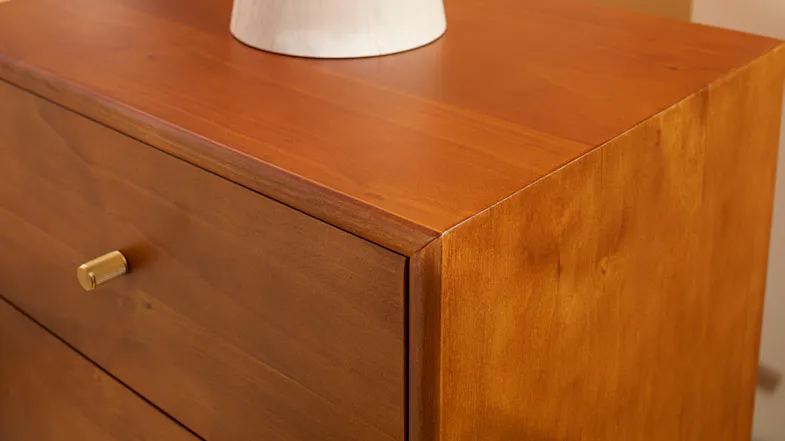 Close-up of warm finish bedside table with brass-look drawer knob and smooth wood grain detail Close-up of warm finish bedside table with brass-look drawer knob and smooth wood grain detail