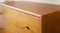 Close-up of wooden dresser corner with warm finish, rounded edges and brass-look handle detail Close-up of wooden dresser corner with warm finish, rounded edges and brass-look handle detail