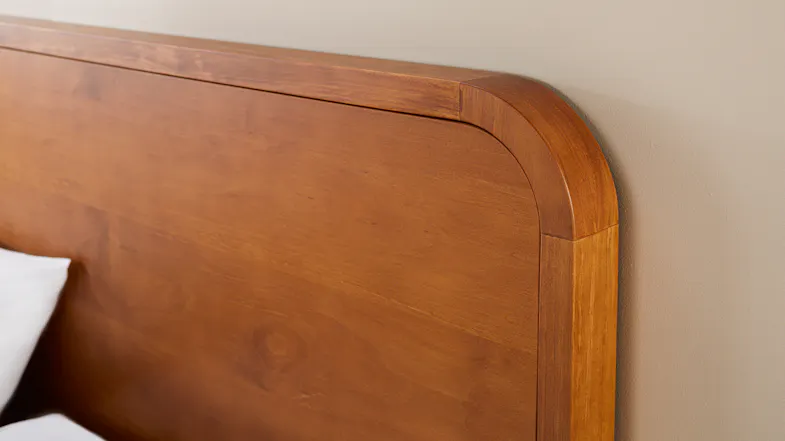 Angled view of the wooden headboard showcasing curved edge and grain texture Angled view of the wooden headboard showcasing curved edge and grain texture