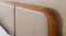 Detailed view of beige extended fabric upholstered headboard with wooden frame and rounded corner design Detailed view of beige extended fabric upholstered headboard with wooden frame and rounded corner design