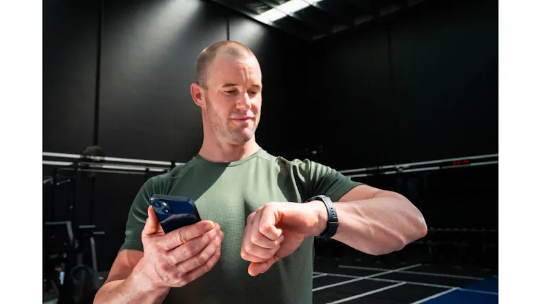 Person in a gym setting wearing a smartwatch while checking workout information Person in a gym setting wearing a smartwatch while checking workout information
