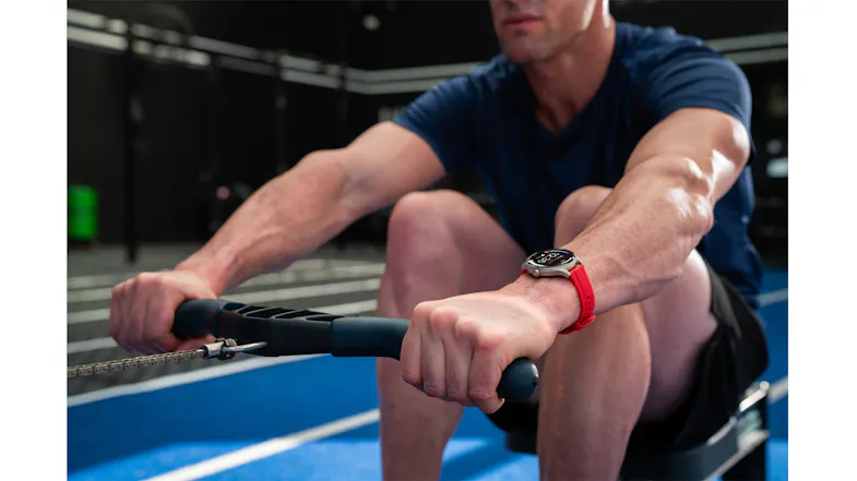 Person using rowing equipment while wearing a smartwatch with a red band Person using rowing equipment while wearing a smartwatch with a red band