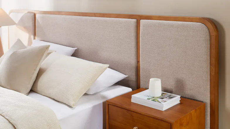 Close-up bedroom view of the Harper Upholstered Extended Headboard featuring textured beige fabric panels Close-up bedroom view of the Harper Upholstered Extended Headboard featuring textured beige fabric panels