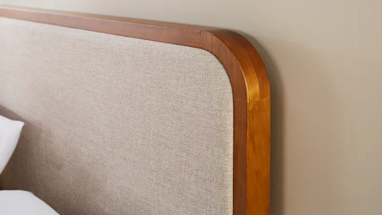 Close-up view of the headboard with round wooden frame and fabric upholstery Close-up view of the headboard with round wooden frame and fabric upholstery