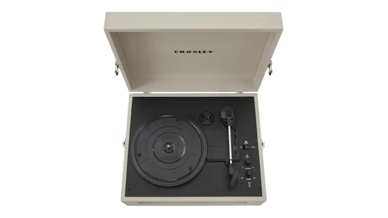 Top-down view of cream portable turntable showing platter, tonearm and control panel with open lid Top-down view of cream portable turntable showing platter, tonearm and control panel with open lid