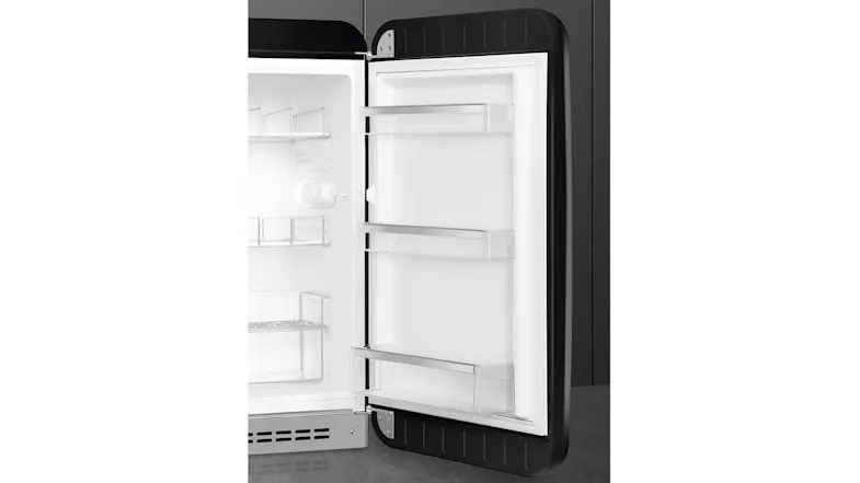 Close-up view of the interior of a black SMEG minibar fridge door, featuring three clear storage racks Close-up view of the interior of a black SMEG minibar fridge door, featuring three clear storage racks