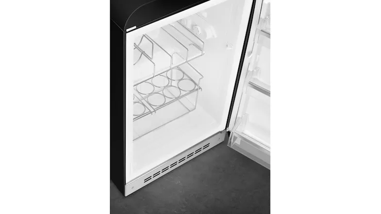 Top-down view of a black SMEG minibar fridge interior with a metal bottle rack and open door Top-down view of a black SMEG minibar fridge interior with a metal bottle rack and open door