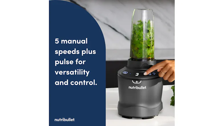 Nutribullet personal blender with a grey base and a clear cup containing leafy greens, operated by a hand pressing Speed 2 Nutribullet personal blender with a grey base and a clear cup containing leafy greens, operated by a hand pressing Speed 2