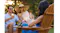 Portable charcoal Shark mist operating on the armrest of a wooden chair, with people relaxing in the background Portable charcoal Shark mist operating on the armrest of a wooden chair, with people relaxing in the background