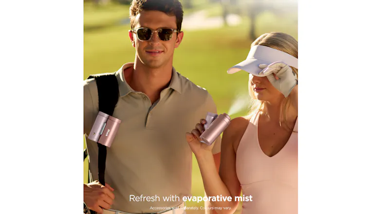 A person holds a rose gold Shark ChillPill misting device on a golf course while spraying a fine mist toward another person A person holds a rose gold Shark ChillPill misting device on a golf course while spraying a fine mist toward another person