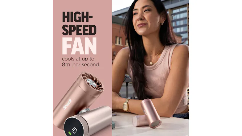 Rose gold Shark ChillPill fan displaying a digital battery screen next to a person sitting at an outdoor table Rose gold Shark ChillPill fan displaying a digital battery screen next to a person sitting at an outdoor table