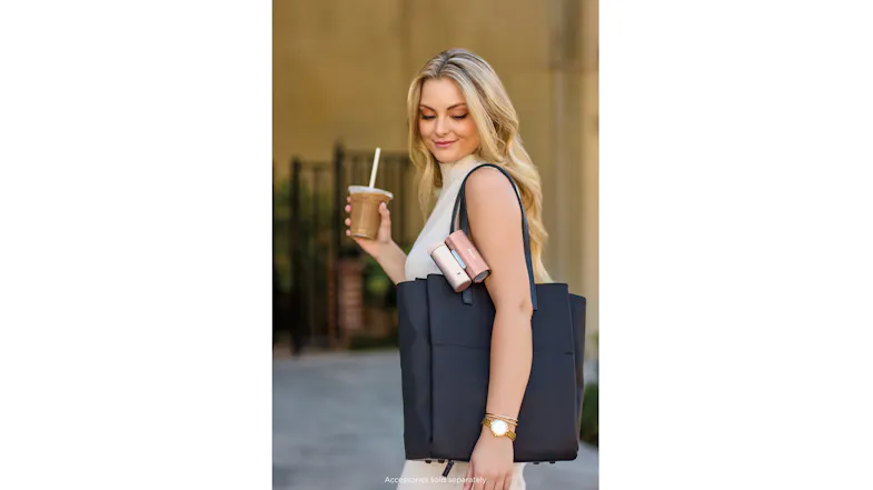 Person carrying a black tote bag with rose gold Shark ChillPill cooling devices attached to the strap Person carrying a black tote bag with rose gold Shark ChillPill cooling devices attached to the strap