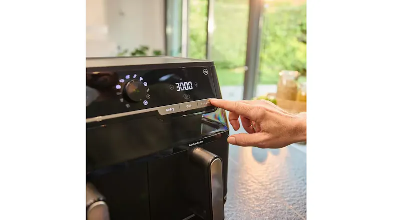 Close-up angled view of a Braun black air fryer touchscreen with a finger selecting the Fast Oven function Close-up angled view of a Braun black air fryer touchscreen with a finger selecting the Fast Oven function
