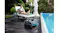 Robotic pool cleaner positioned beside a swimming pool with poolside seating in the background Robotic pool cleaner positioned beside a swimming pool with poolside seating in the background
