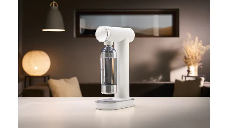 Soda water maker in matte white displayed on a kitchen benchtop with a reusable bottle attached Soda water maker in matte white displayed on a kitchen benchtop with a reusable bottle attached