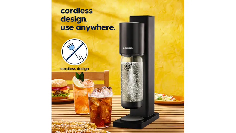 Front angled view of a black SodaStream Water Maker with a carbonating bottle on an outdoor dining table Front angled view of a black SodaStream Water Maker with a carbonating bottle on an outdoor dining table